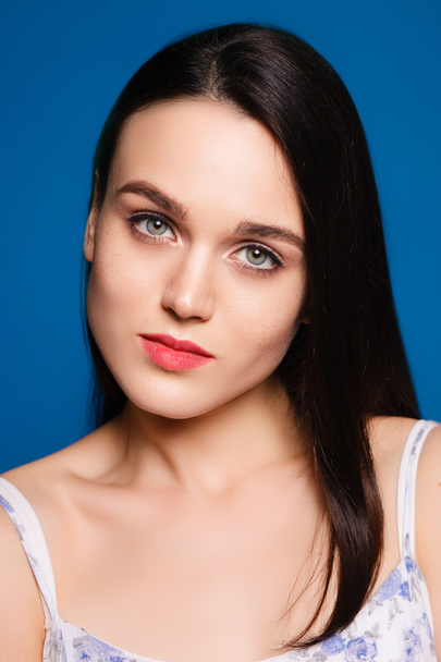 beautiful young brunette woman on a blue background  - Valokuva, kuva