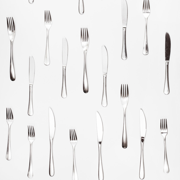 table knives and forks arranged on white - Foto, afbeelding