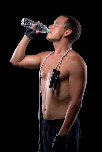 красивый мускулистый спортсмен пьет воду из бутылки после поезда
 - Фото, изображение