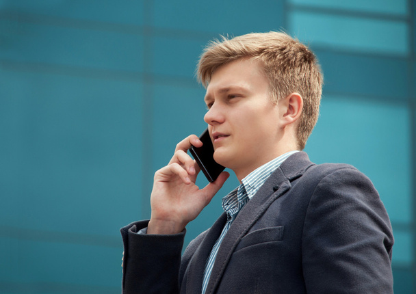 Homme d'affaires parlant sur un smartphone près d'un bâtiment moderne
 - Photo, image
