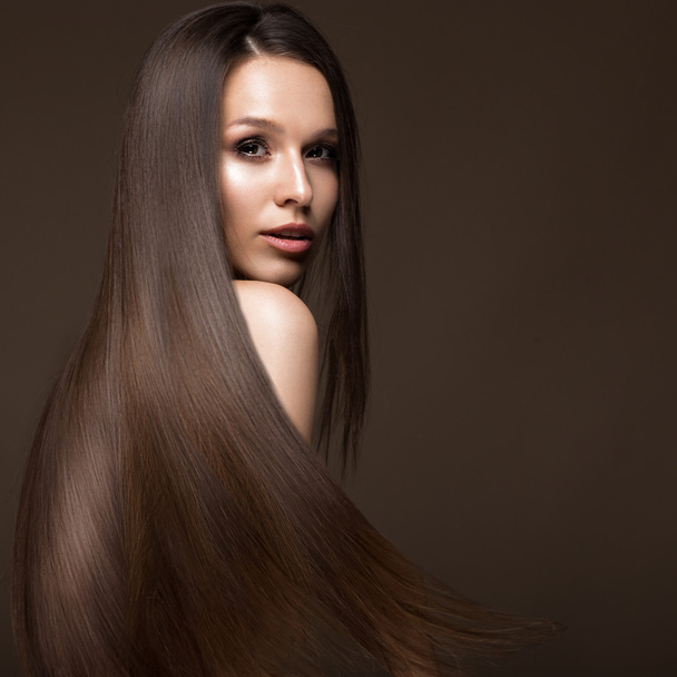 Beautiful brunette girl in move with a perfectly smooth hair, and classic make-up. Beauty face. - Zdjęcie, obraz