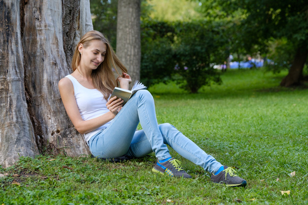 mujer joven leyendo un libro en el parque - Foto, Imagen