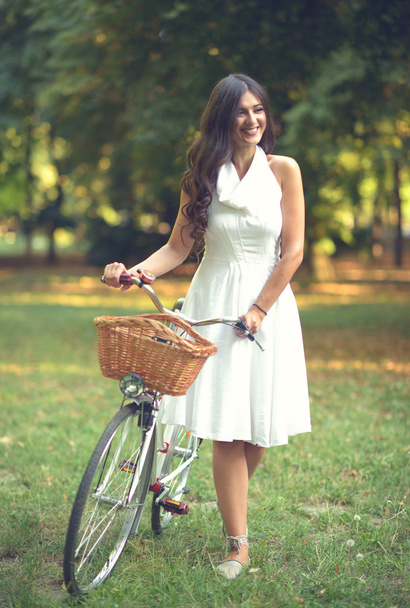 Beautiful woman riding bicylce in park and enjoying beautiful su - Photo, Image