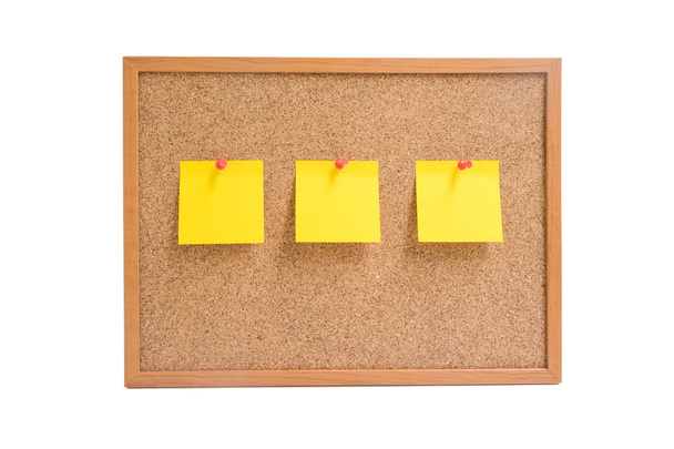 Απομονωμένη ξύλινη σανίδα με τρεις κίτρινες κολλώδεις σημειώσεις pin για το  - Φωτογραφία, εικόνα