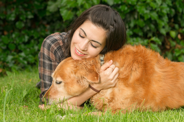 Μελαχρινή γυναίκα υμνούν της Golden Retriever σκύλου σκύλων - Φωτογραφία, εικόνα