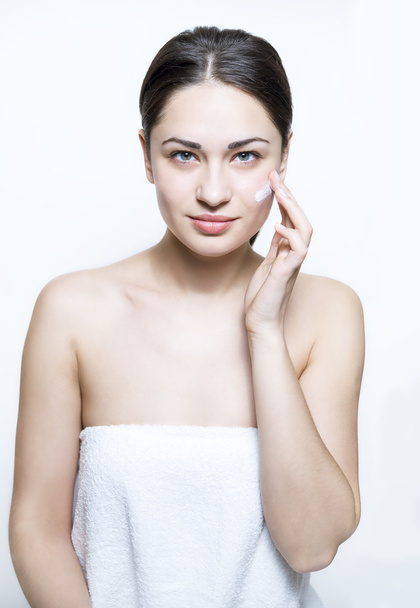 beautiful girl apply cream on the face during a spa - Fotó, kép