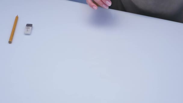 Human hands with pencil writing on paper on white table background - Video, Çekim