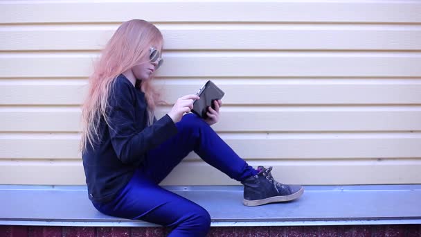 Schoolgirl Sitting Sideway on the Edge Looking Into the Tablet - Záběry, video