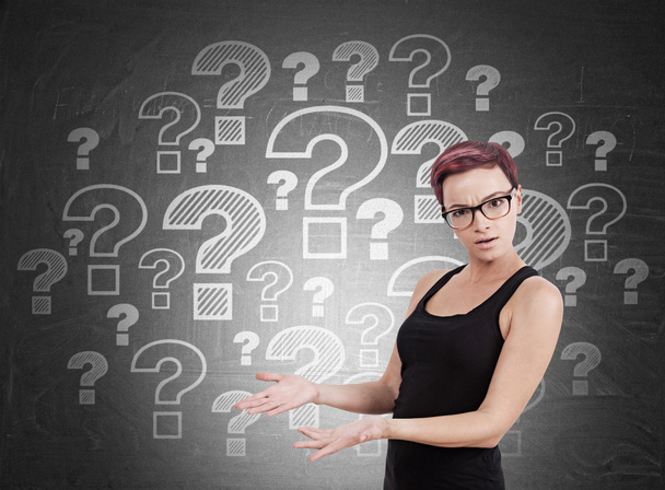 Woman standing near blackboard with question marks - Photo, Image