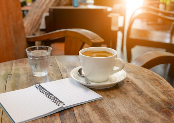Coffee with notebook and water glass on wooden table. - Foto, immagini