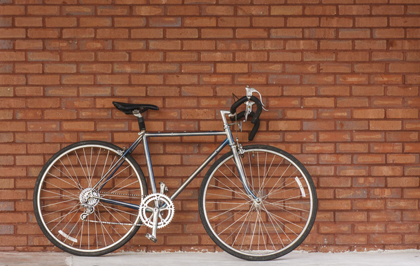 Bicicleta vieja apoyada contra la pared de ladrillo rojo
 - Foto, imagen