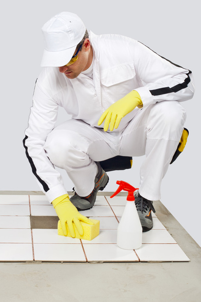 εργάτης καθαρίζει με σφουγγάρι και σπρέι παλιά πλακάκια δαπέδου - Φωτογραφία, εικόνα
