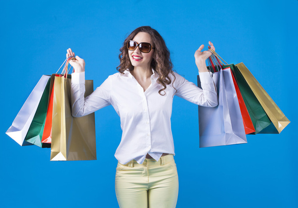 Girl with shopping bags on blue background. - Foto, Imagen