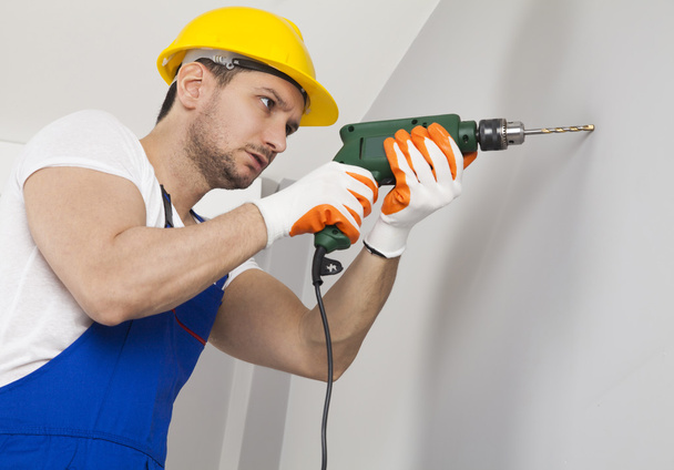Young man drilling hole in wall - Photo, Image
