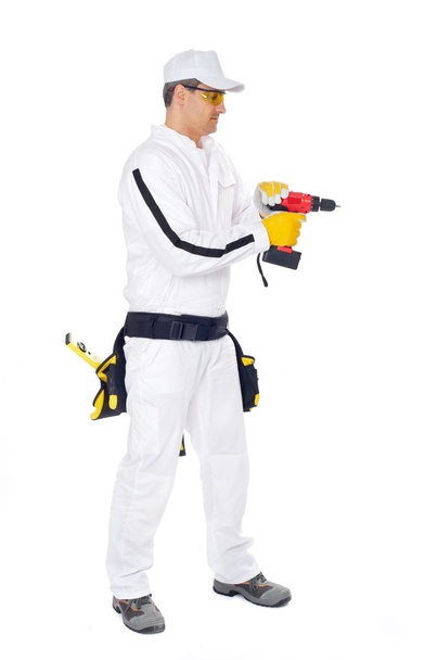 werknemer in witte Amerikaanse overalls met een rode boren gat boren - Foto, afbeelding