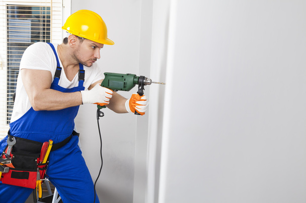 Young man drilling hole in wall - Foto, Imagem