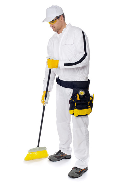 Construction worker in white overalls sweeping with a broom - Photo, Image