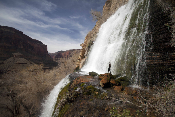 Водопад с мужчиной, поднимающим оружие
 - Фото, изображение