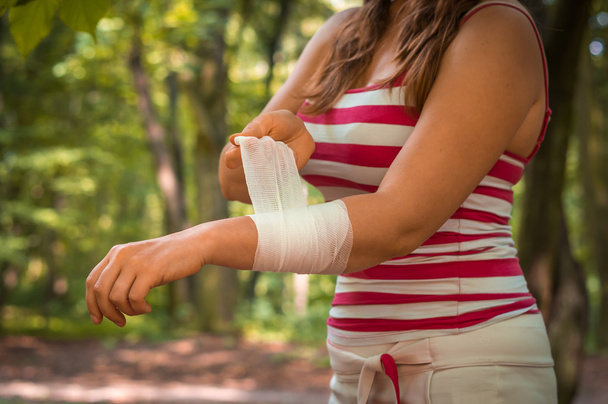 Женщина накладывает повязку на руку после травмы
 - Фото, изображение