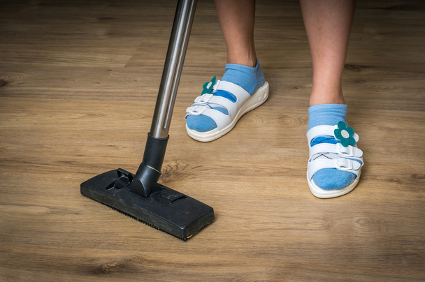 Woman with vacuum cleaner cleaning wooden laminate floor - Photo, Image