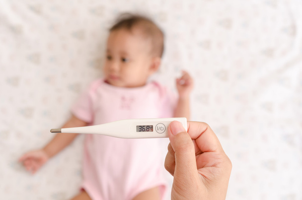 Asiatische Babytemperatur mit digitalem Thermometer messen - Foto, Bild