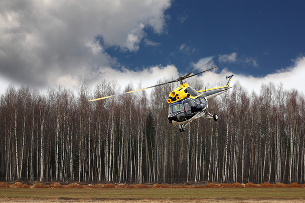 Літаки - Чорно-жовтий вертоліт здійснює політ на низькій висоті
 - Фото, зображення
