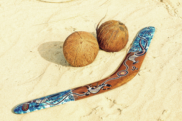 Color boomerang and two coconuts on sandy beach taken closeup. - Fotografie, Obrázek