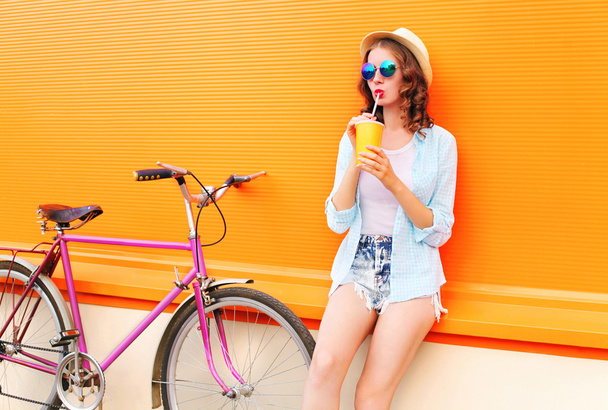 Fashion pretty woman drinks fruit juice from cup with retro bicy - Foto, imagen