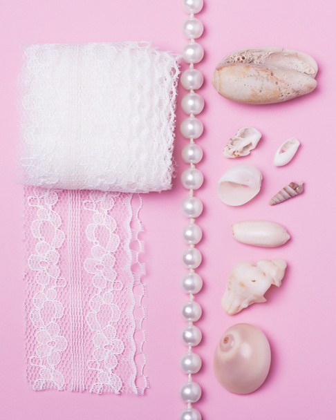 Conchas do mar, pérolas e rendas sobre um fundo rosa
 - Foto, Imagem