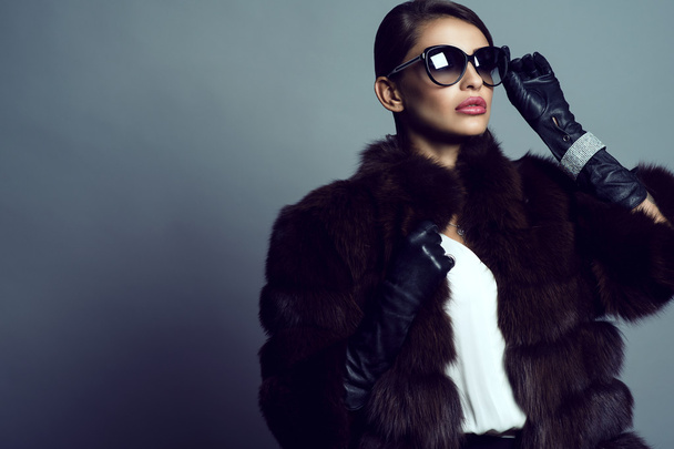 Beautiful glam model wearing white silk blouse, sable coat, leather gloves, sunglasses and set of luxurious bracelet, ring and silver chain with pendant. - Photo, Image