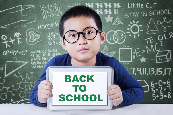 Schoolboy shows a text of back to school in class - Φωτογραφία, εικόνα