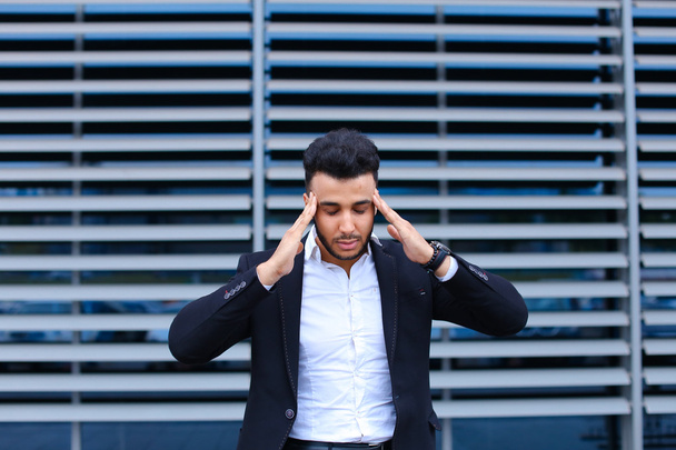 Young arabic man shows neck pain tired in business center - Photo, image