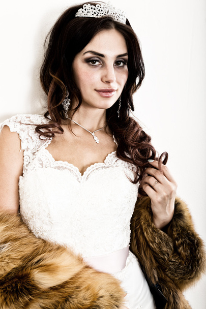 close-up portrait of young beautiful bride in a wedding dress with a wedding makeup and hairstyle. young bride in a fur coat from a red fur - Foto, immagini