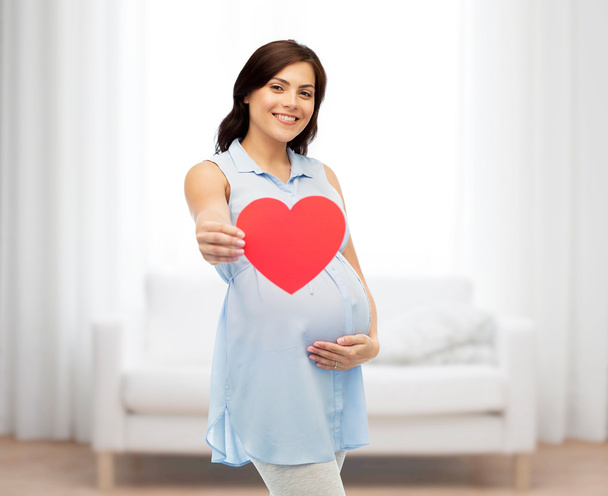 happy pregnant woman with red heart touching belly - Zdjęcie, obraz