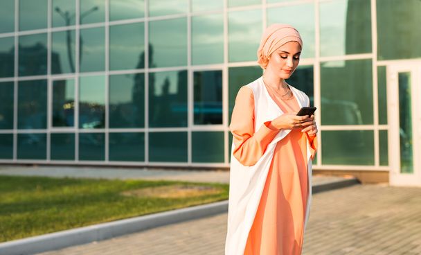 Donna musulmana messaggistica su un telefono cellulare in città
 - Foto, immagini
