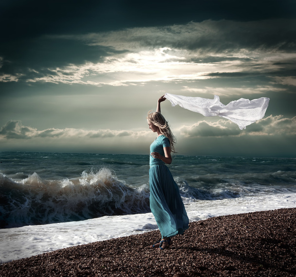 Ξανθιά γυναίκα στο μακρύ φόρεμα στη φουρτουνιασμένη θάλασσα - Φωτογραφία, εικόνα