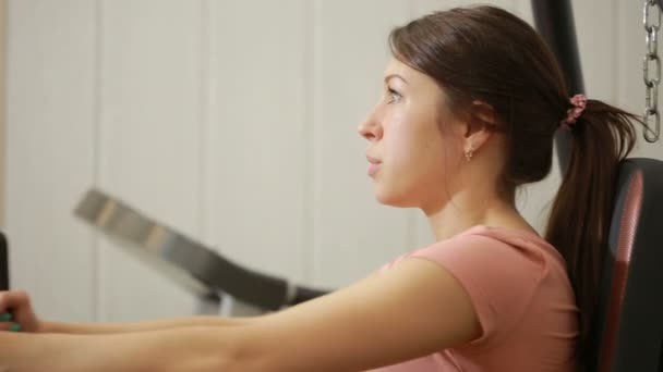 Beautiful girl trains in the gym. woman engaged in a sports simulator - Video