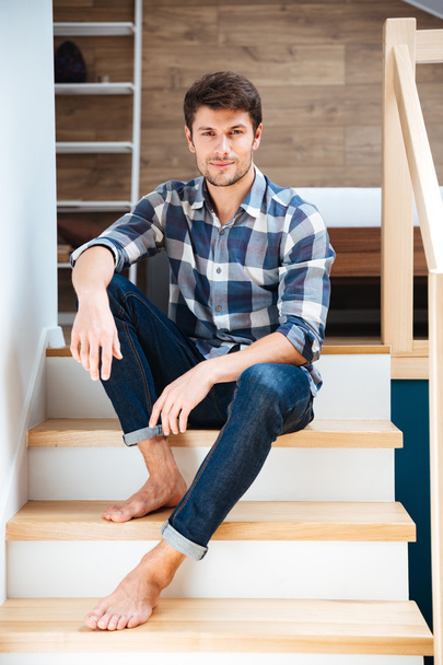 Portrait of a young handsome man sitting on the staircase - 写真・画像