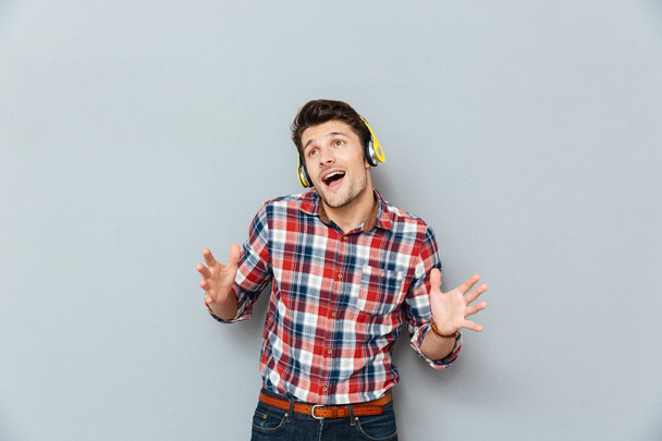 Happy young man in headphones listening to music and singing - Foto, Imagem