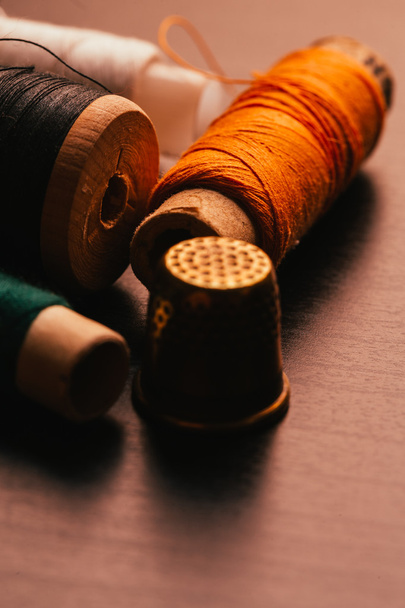spools of thread and a thimble on wooden background - Фото, зображення
