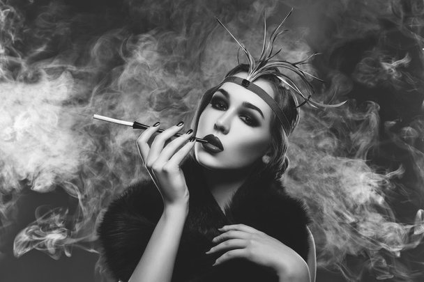 Όμορφο κορίτσι με καπνιστή μάτια και κόκκινα χείλη, κρατώντας τσιγάρο - Φωτογραφία, εικόνα