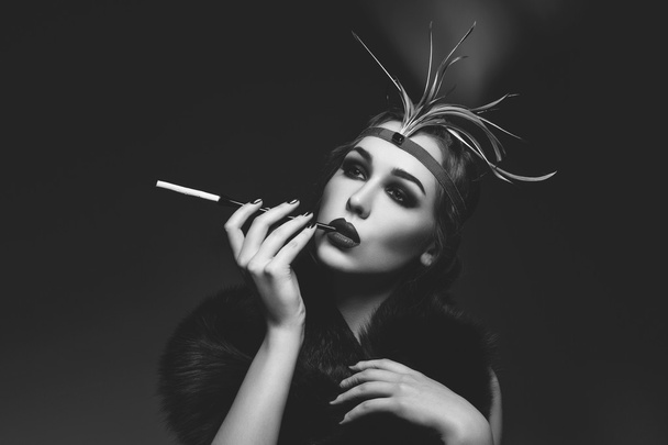 Beautiful girl with smoky eyes and red lips holding cigarette - Фото, изображение