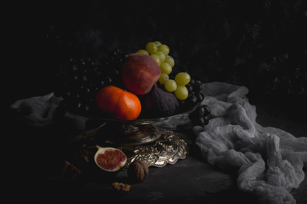 Still life. Autumn fruits in a beautiful vase. Honey, nuts, vintage tongs. - Photo, Image