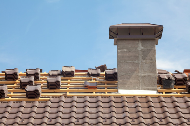 Un techo en construcción con pilas de tejas listas para sujetar
 - Foto, imagen