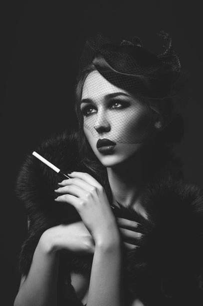 Menina bonita com olhos fumegantes e lábios vermelhos segurando cigarro
 - Foto, Imagem