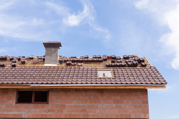 Un tetto con camino in costruzione con pile di tegole pronte per il fissaggio
 - Foto, immagini