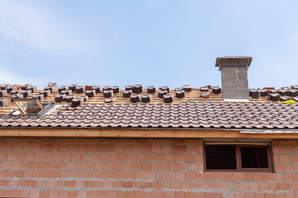 Een dak met een schoorsteen in aanbouw met stapels van dakpannen klaar te bevestigen - Foto, afbeelding