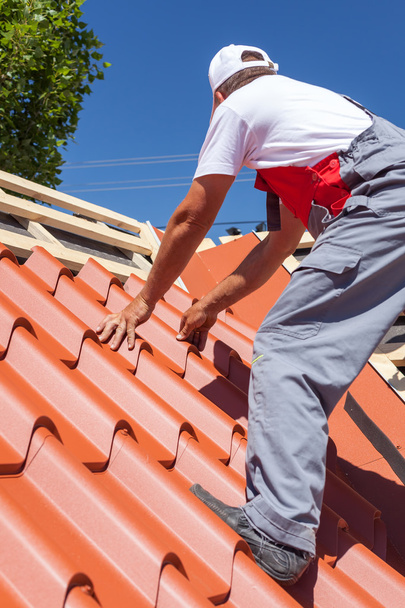 木造でタイルを張り電気ドリル インストール赤い金属屋根上の労働者 - 写真・画像