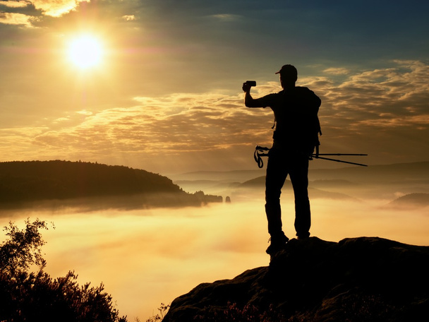 Hombre fuerte excursionista tomando fotos con teléfono inteligente en el pico de la montaña
. - Foto, Imagen
