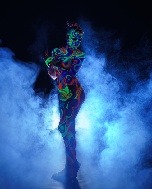 Girl with body art poses in UV light and smoke - Foto, afbeelding